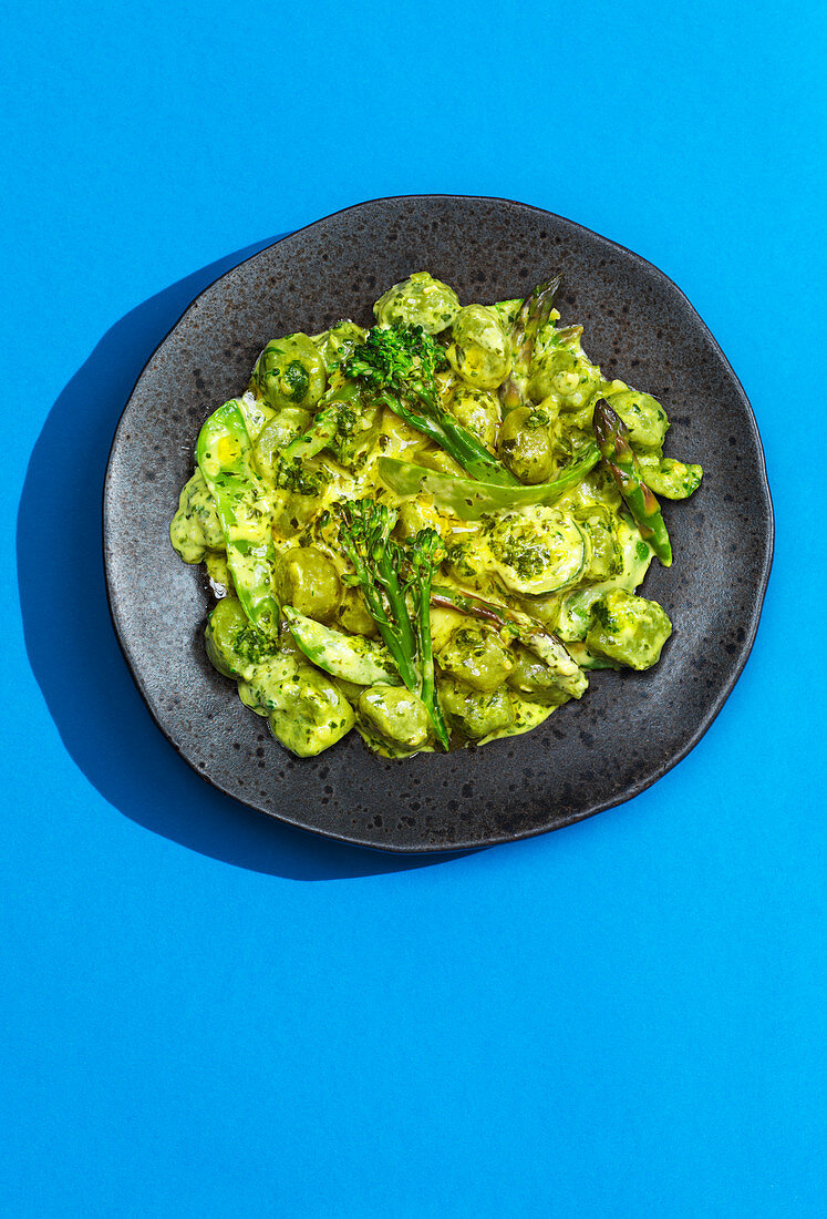 Gnocchi mit grünem Gemüse auf blauem Untergrund