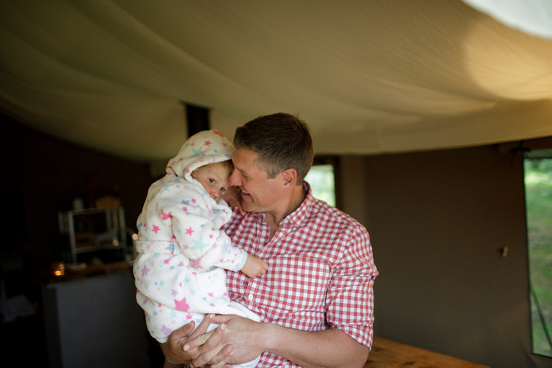 Father holding daughter in bathrobe in yurt