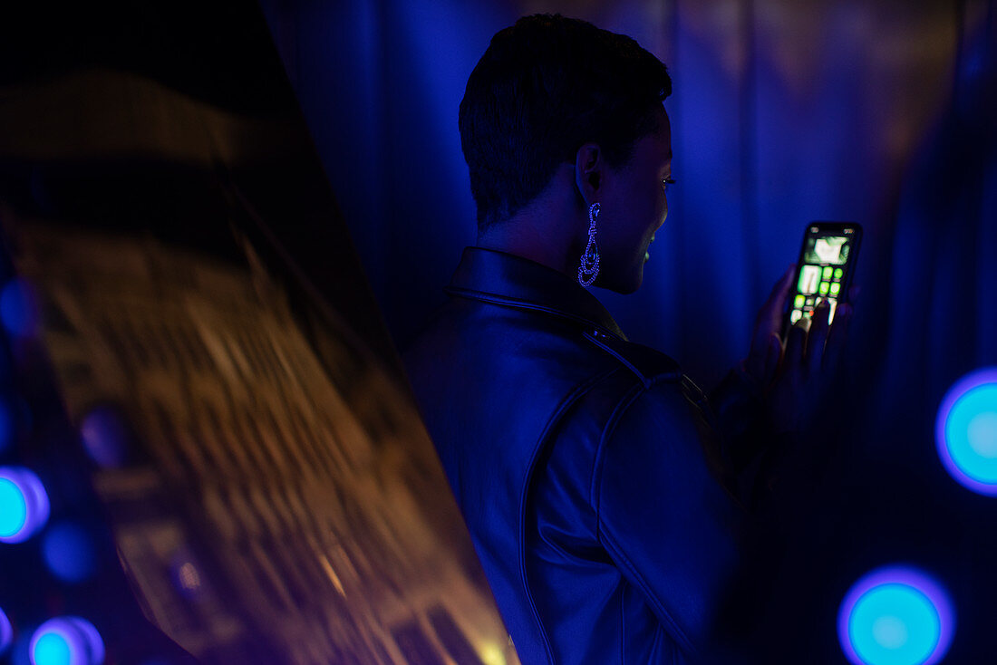 Young woman using smartphone in dark blue light