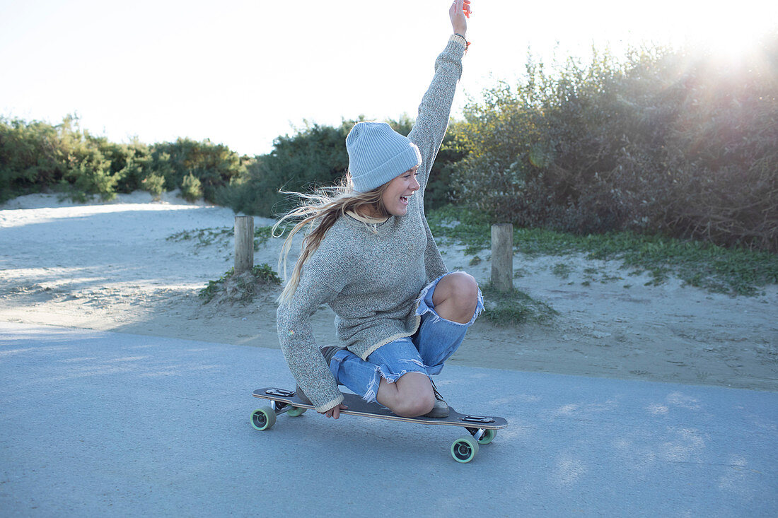 Young woman skateboarding on a beach path