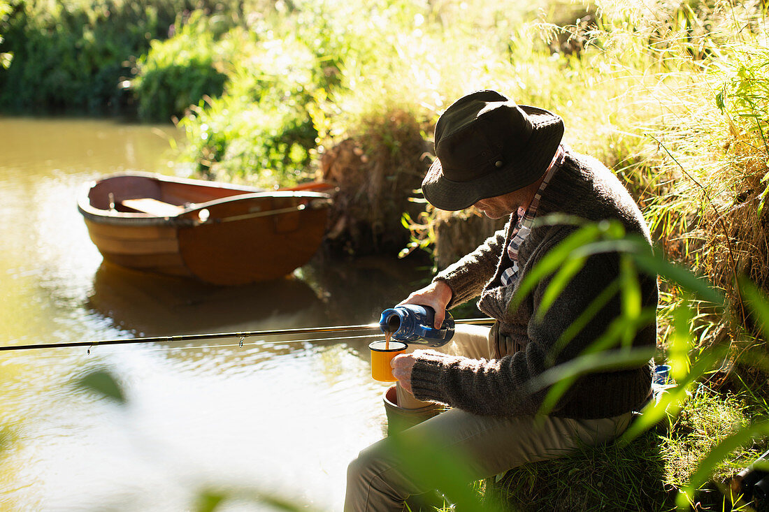 Man fly fishing and pouring coffee at sunny river
