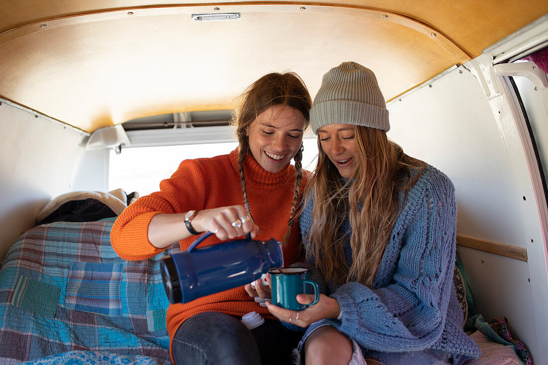 Young women friends enjoying coffee in camper van