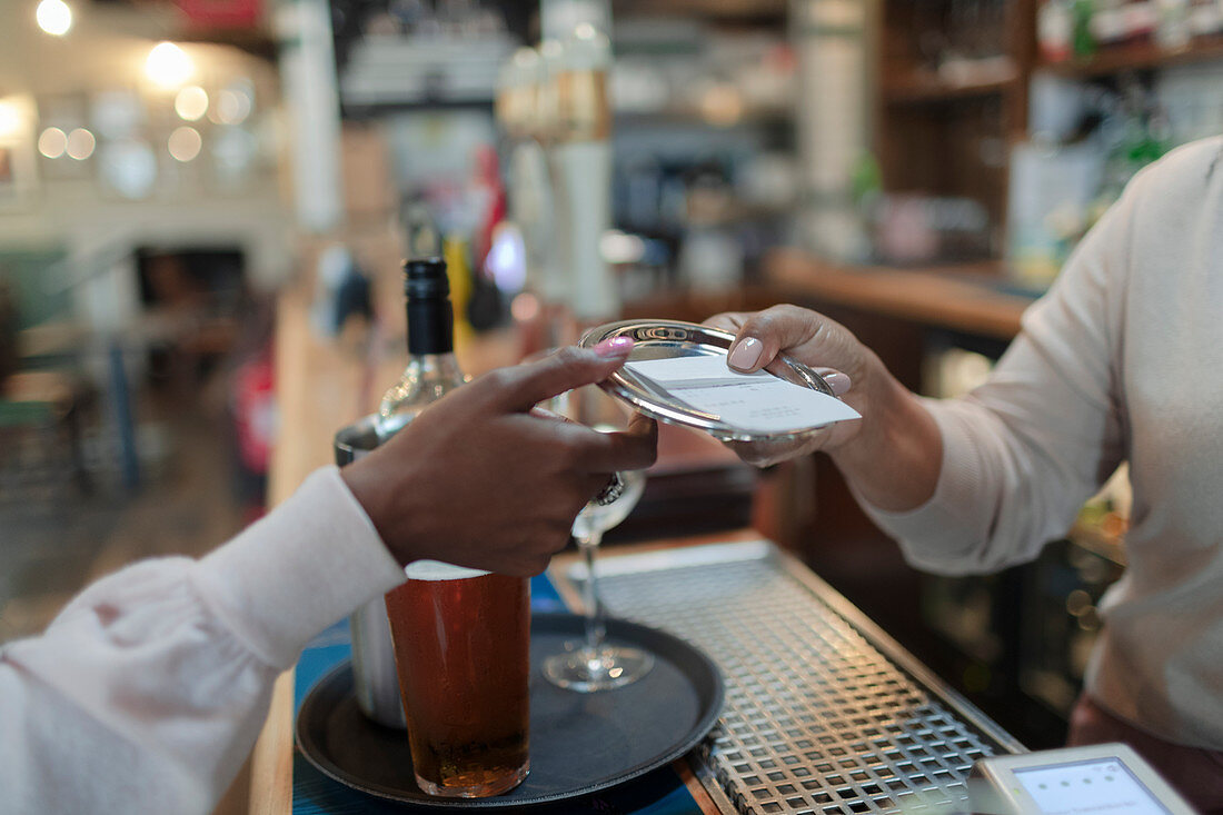Bartender giving bill to customer in pub