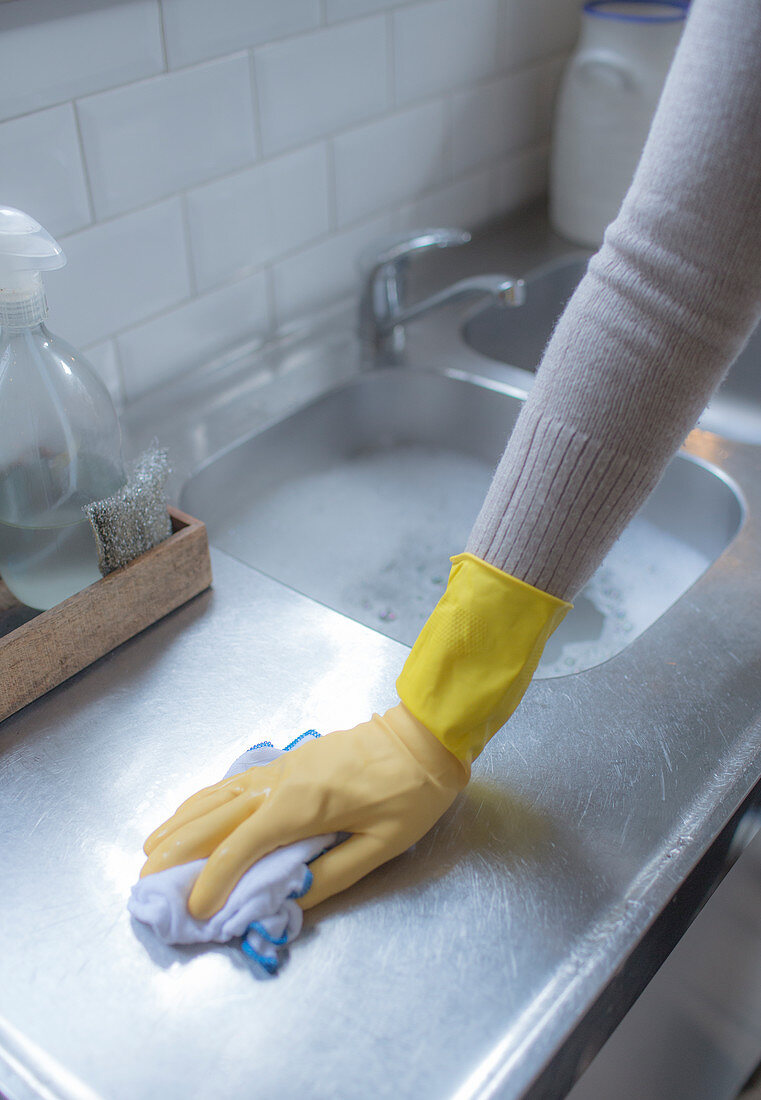 Woman in rubber glove cleaning kitchen counter