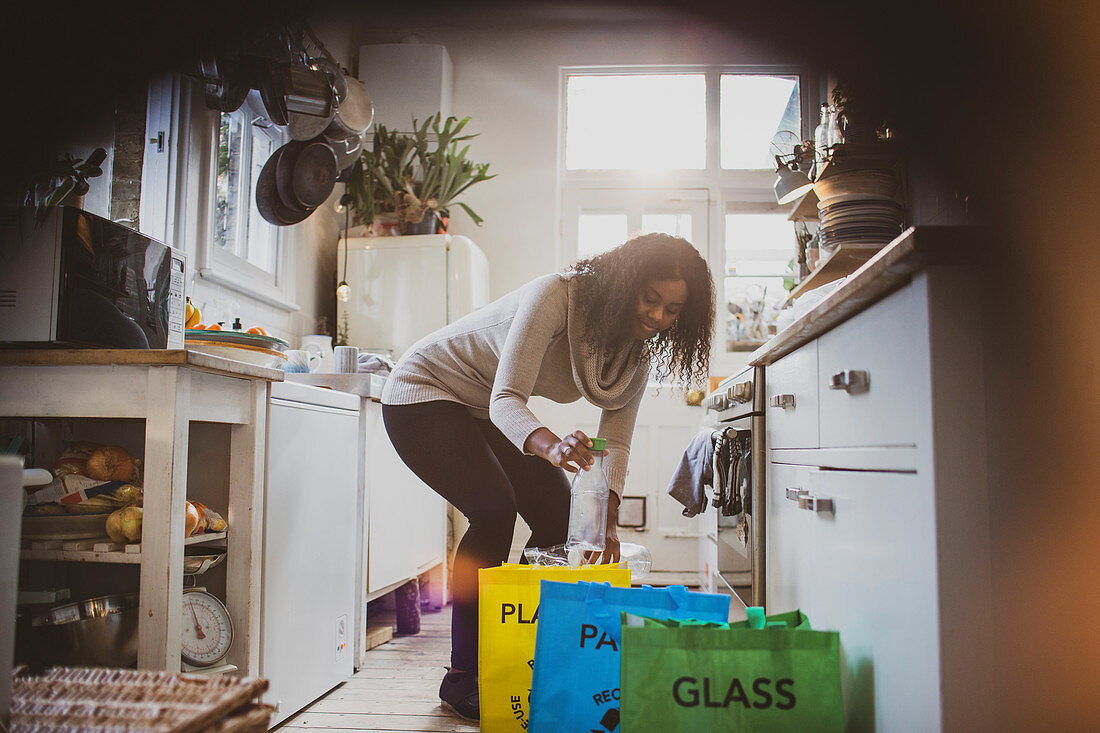 Young woman sorting recycling on kitchen floor