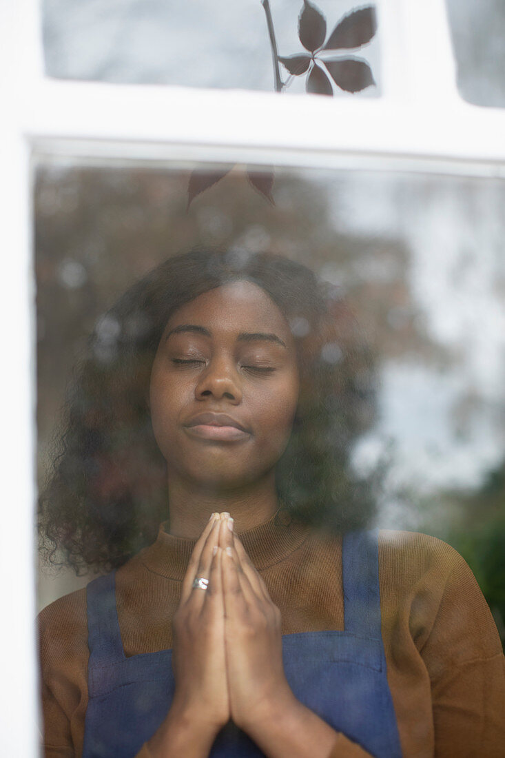 Young woman praying at window