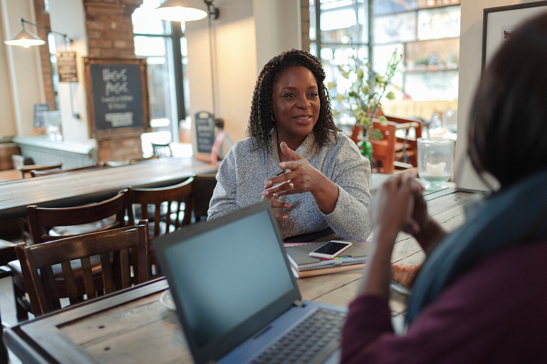 Businesswomen meeting and talking at laptop in cafe