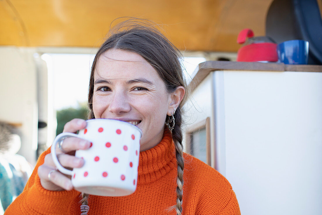 Happy young woman drinking tea in camper van