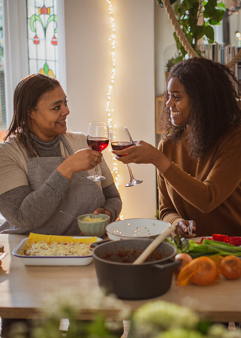 Mother and daughter cooking and drinking wine at home