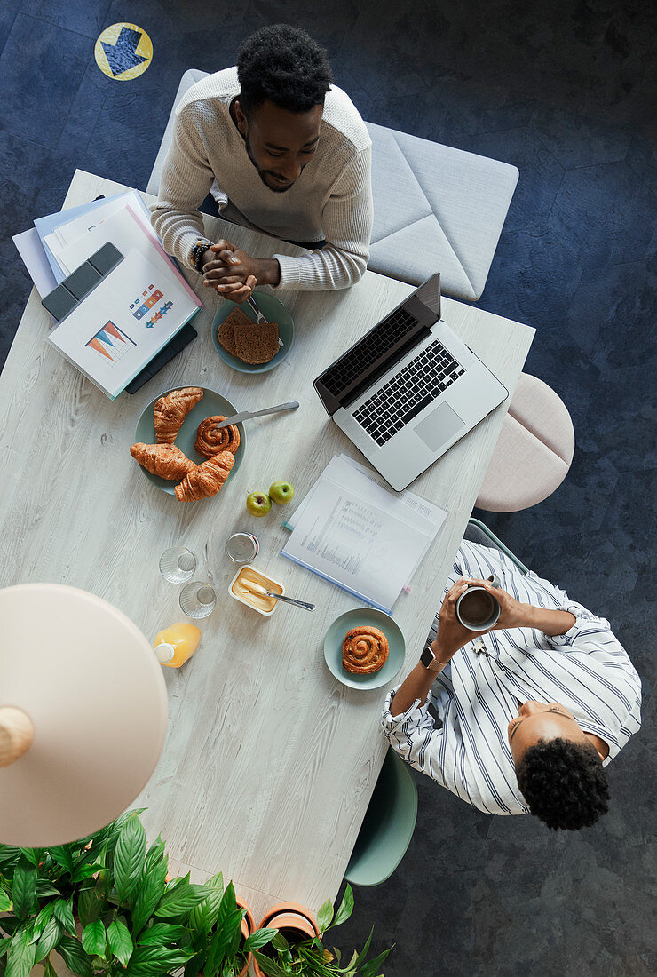 Business people talking over breakfast at office table