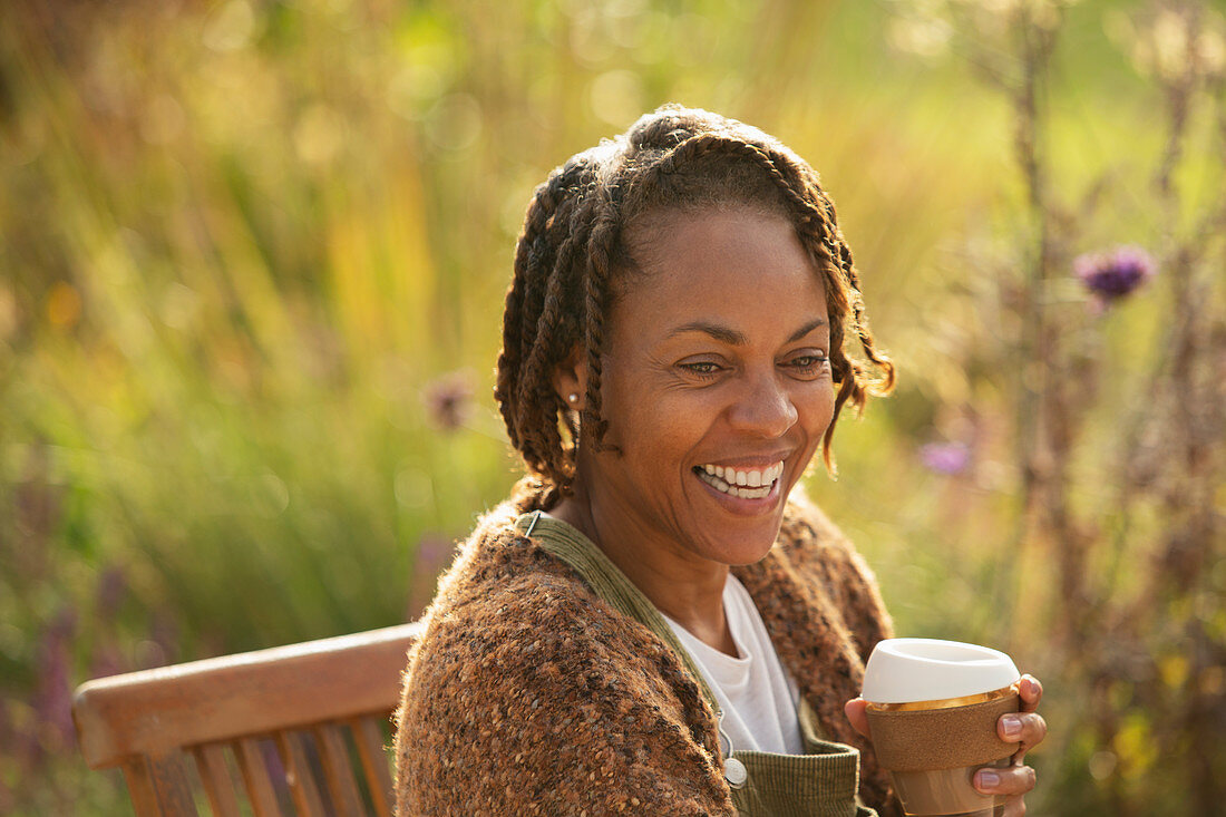Happy woman with coffee laughing on sunny garden patio