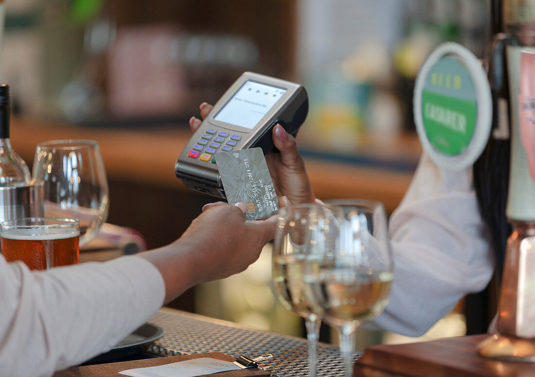 Customer paying bartender with smart card in bar