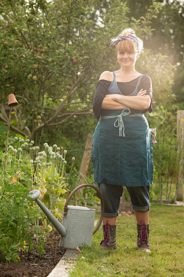Confident woman with watering can in summer garden