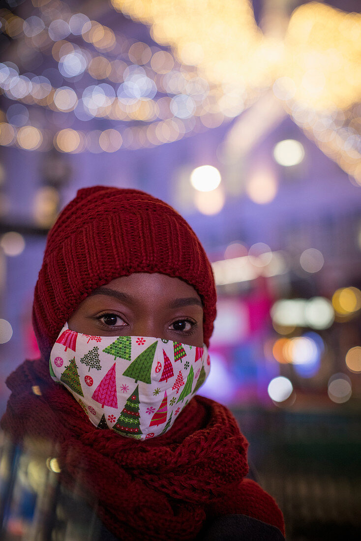 Young woman in christmas face mask in city at night
