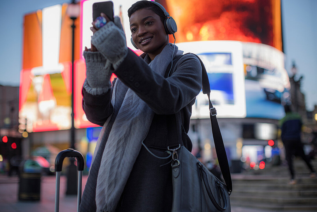 Young woman taking selfie on city street at night