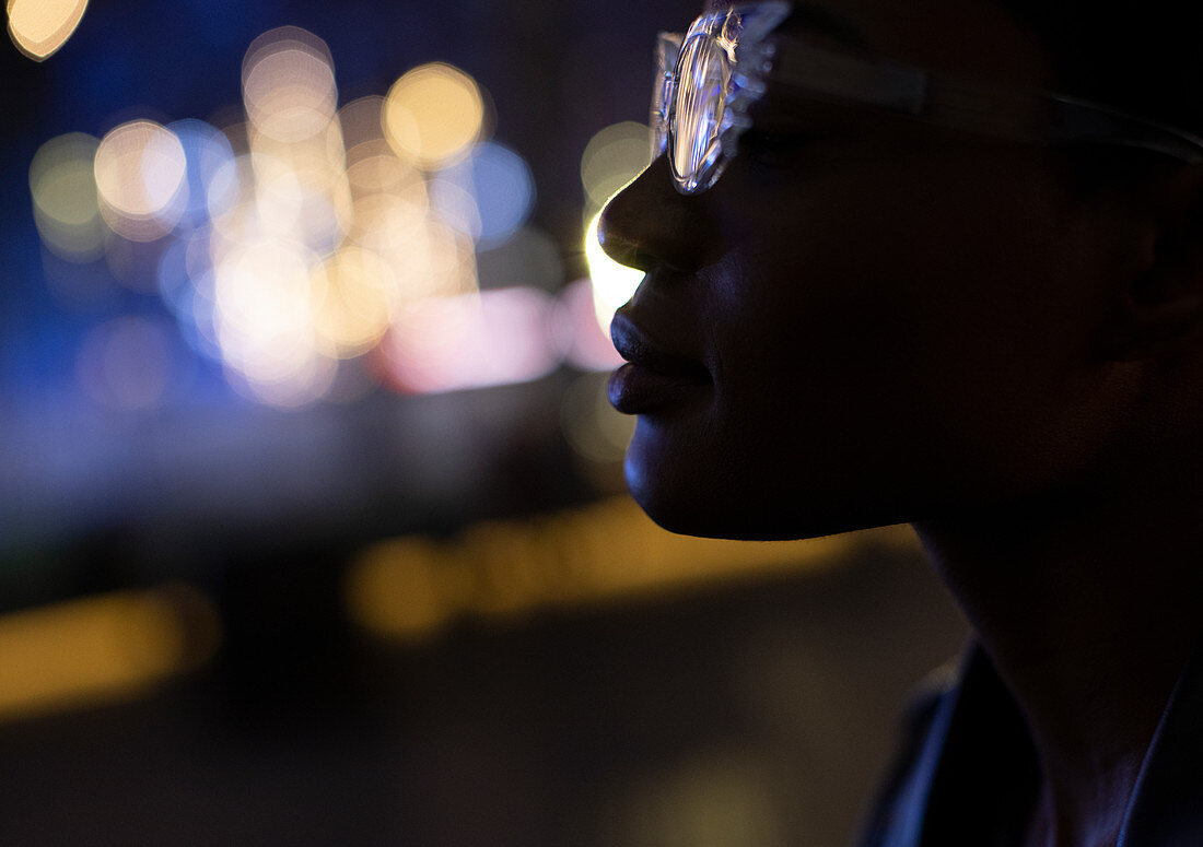 Young woman in stylish glasses at night