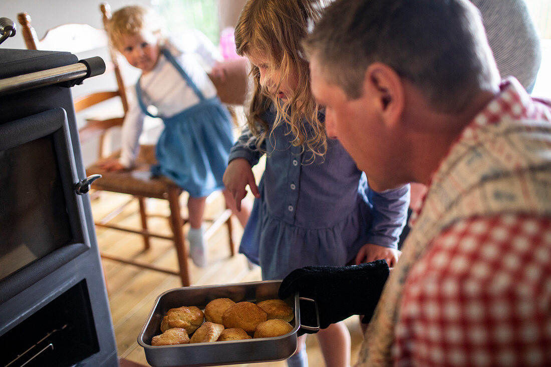 Father and daughter removing fresh biscuits from oven