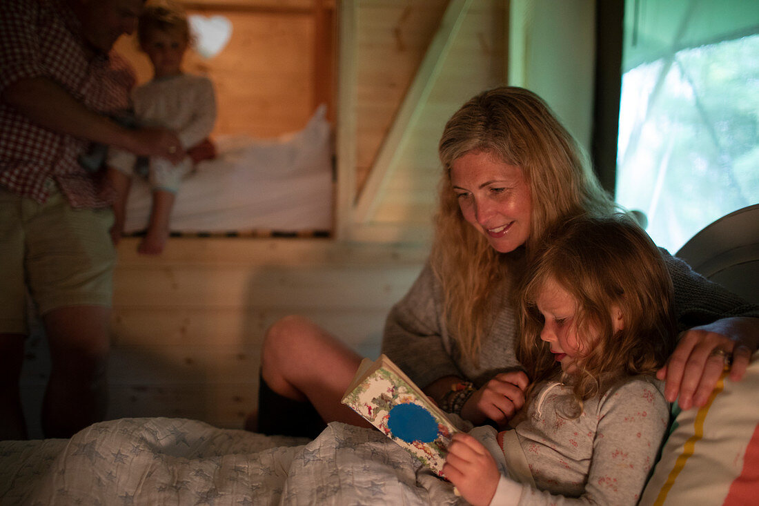 Mother and daughter reading bedtime story book in bed