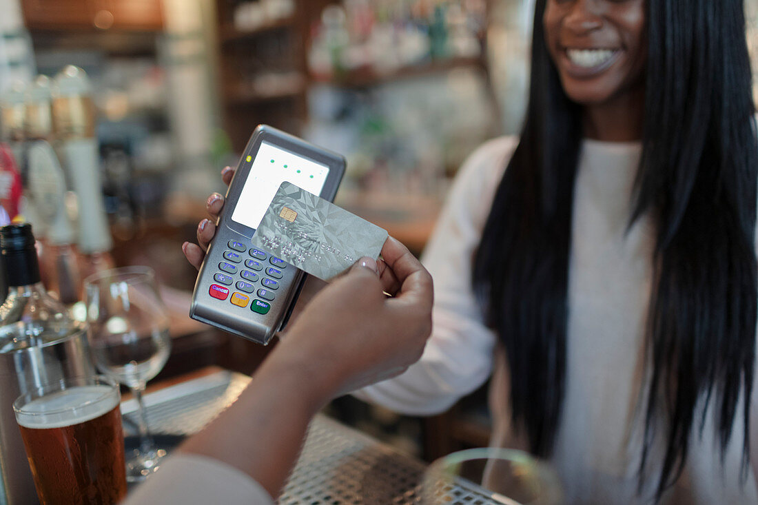 Customer paying female bartender with smart card in pub