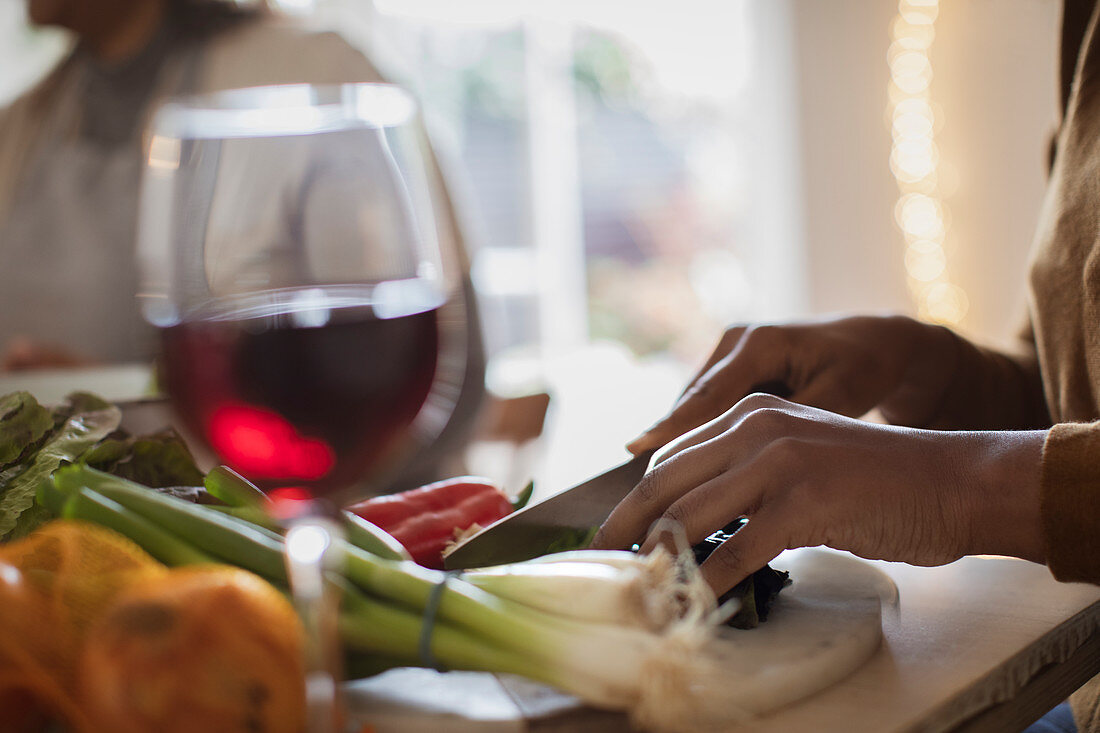 Woman with red wine slicing vegetables on cutting board