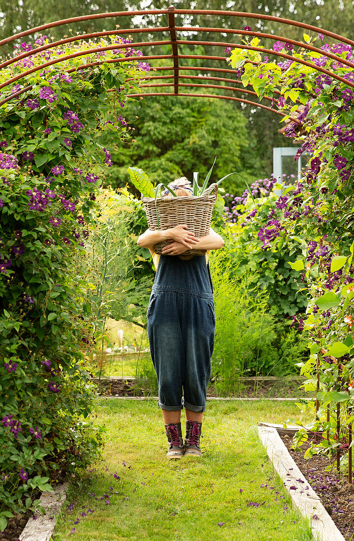 Woman holding large basket of harvested garden vegetables