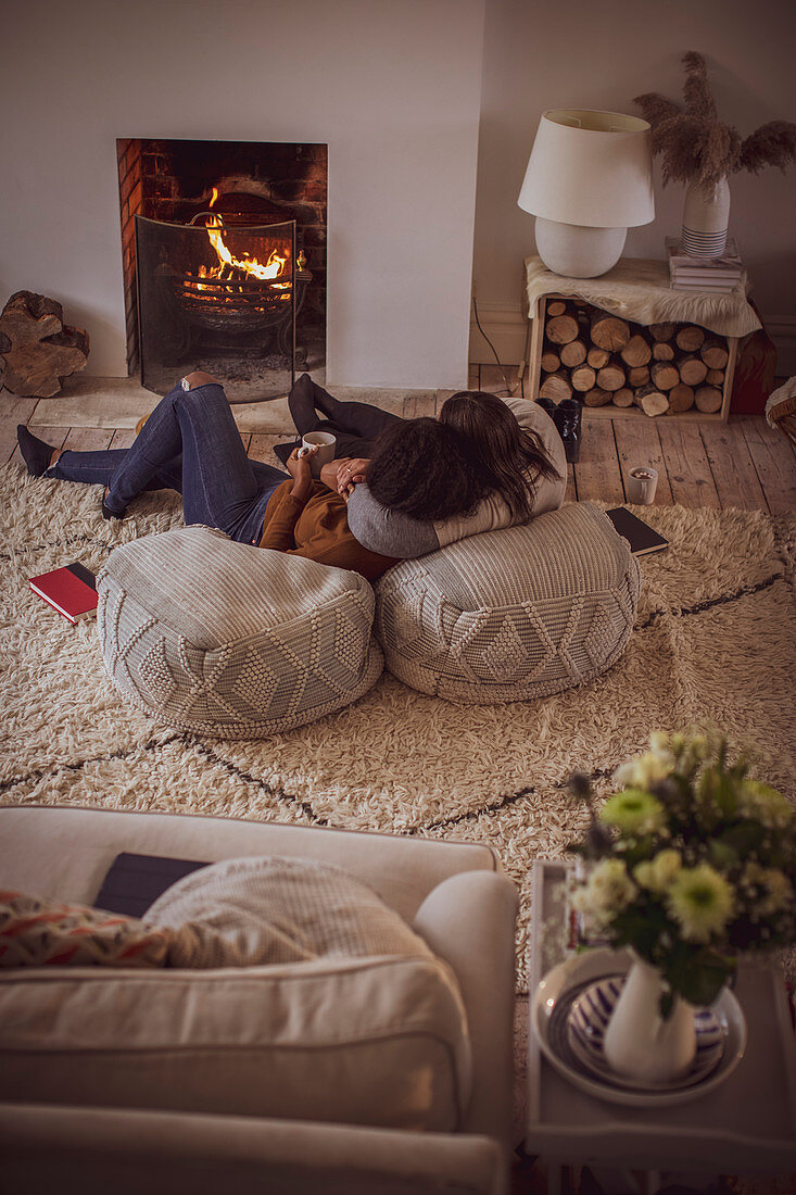 mother and daughter cuddling by fireplace with coffee