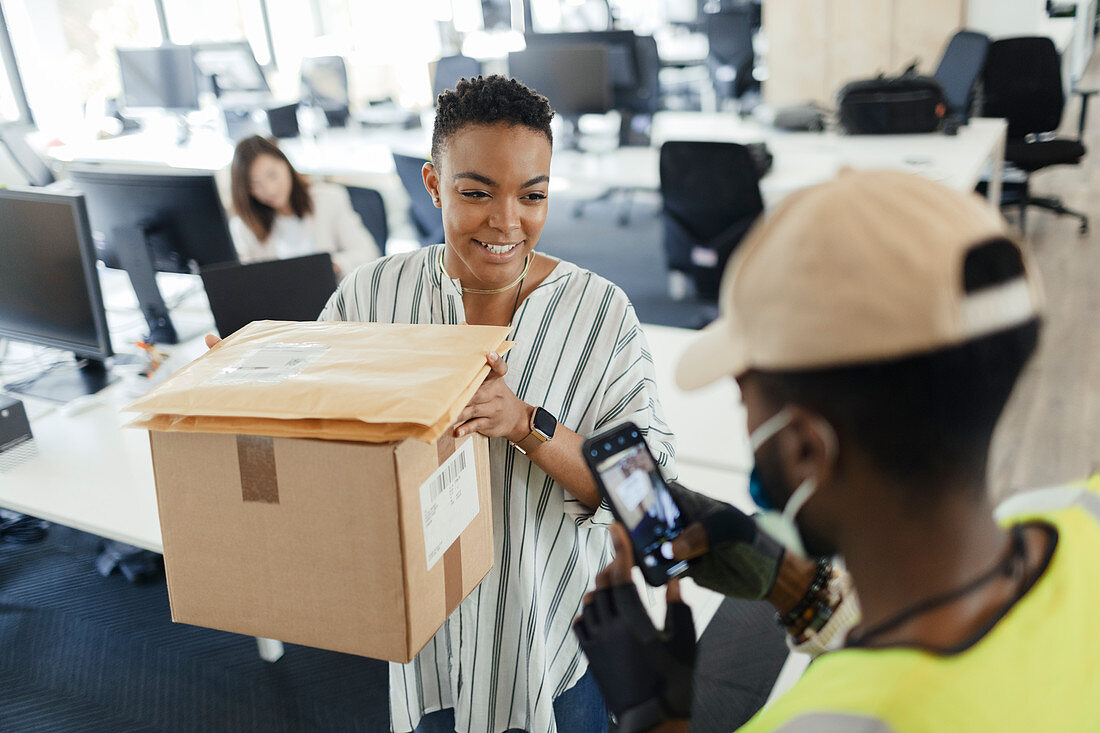 Woman receiving packages from courier with smartphone