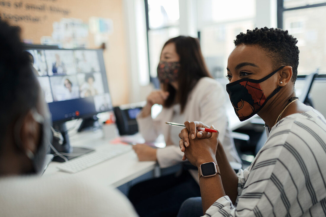 Business people in facemasks video conferencing at office