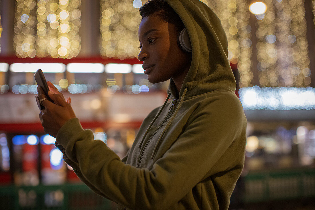 Young woman using a smartphone on city street at night