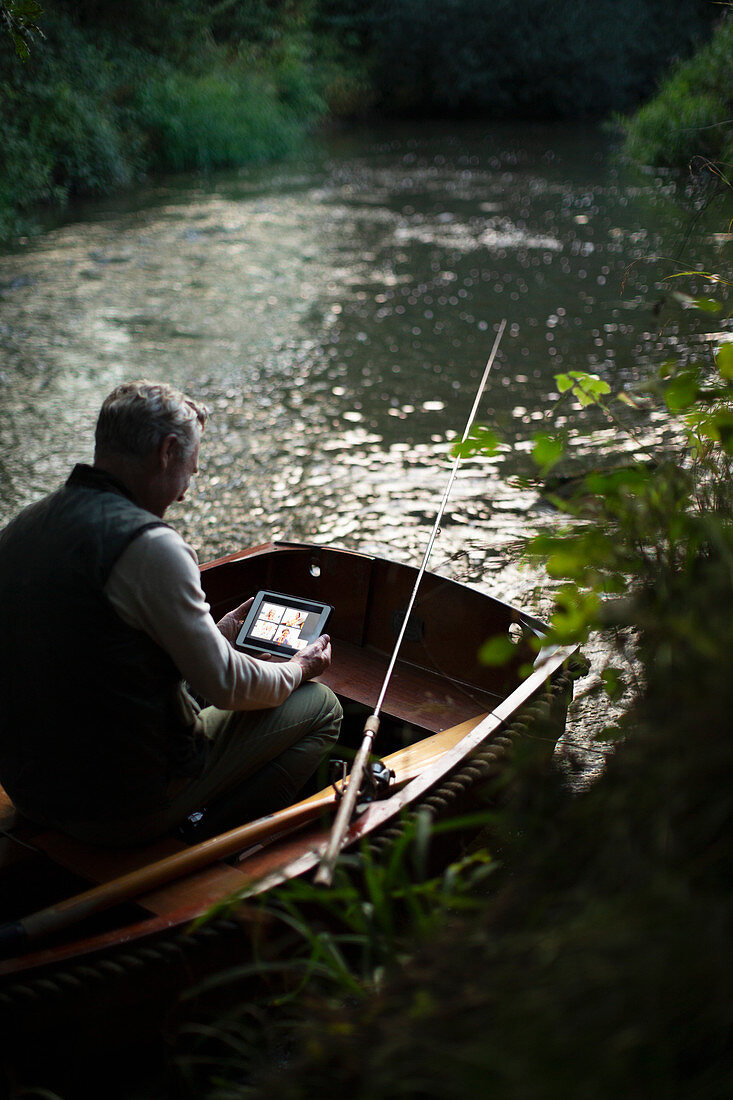 Man fly fishing and video chatting with a tablet in boat