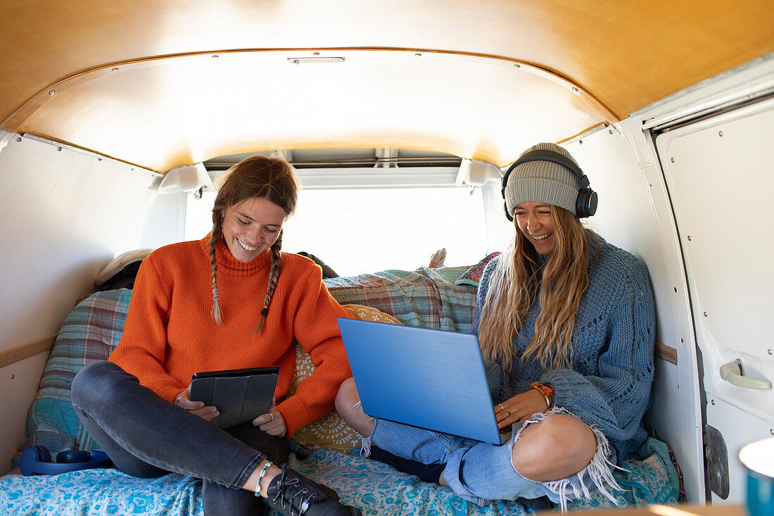 Friends relaxing with technology inside camper van