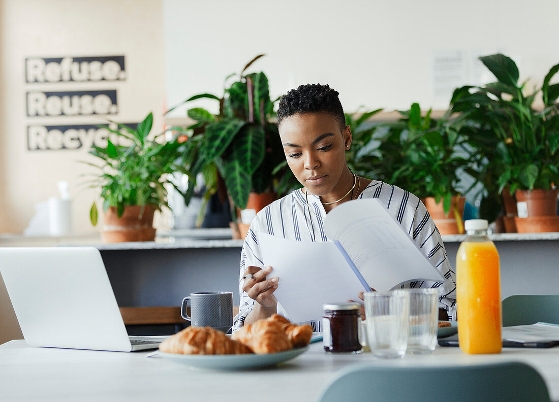 Businesswoman reviewing paperwork at breakfast in lounge
