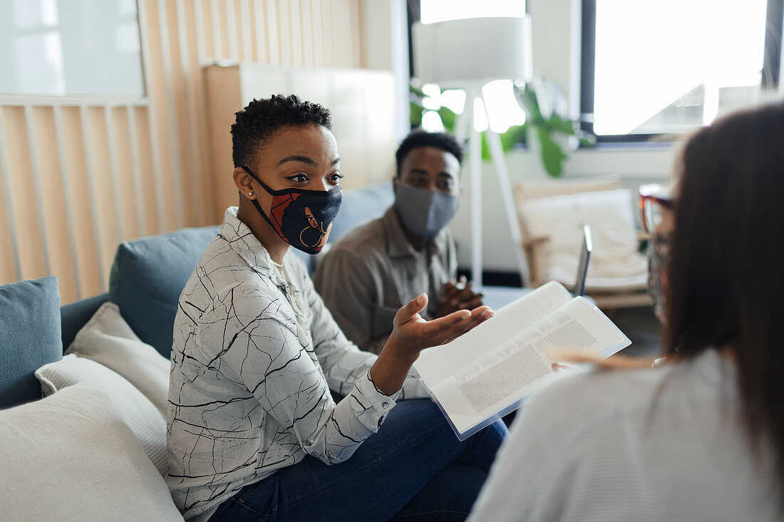 Business people in facemasks discussing paperwork in meeting