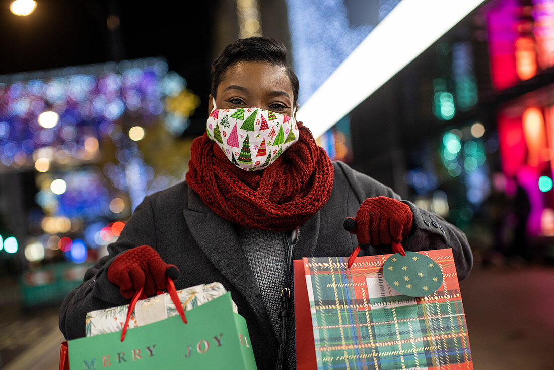Happy young woman in Christmas facemasks shopping at night