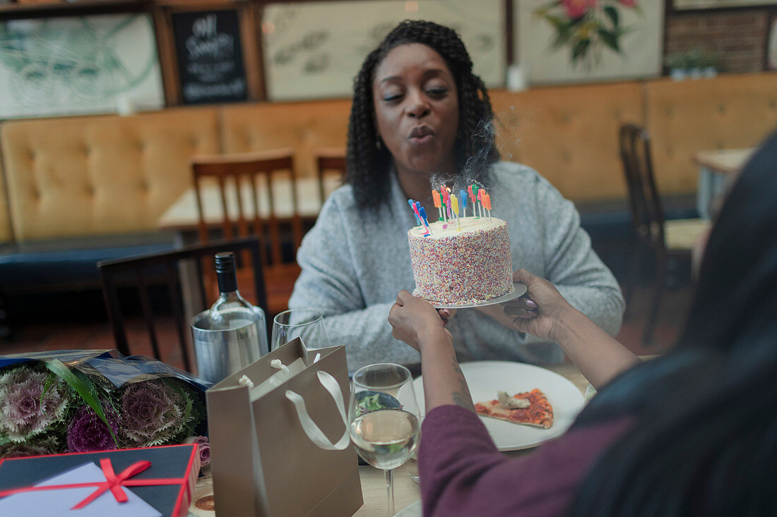 Mother blowing out birthday candle on cake with daughter