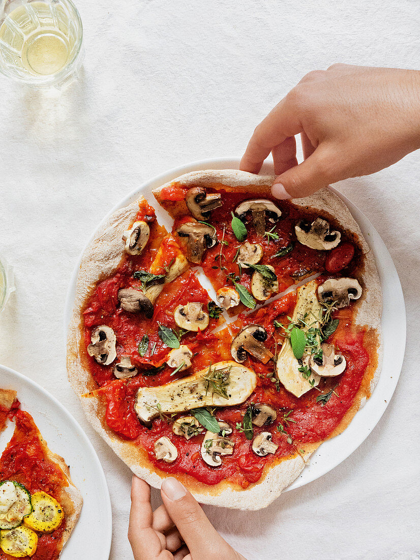 Pizza mit Tomatensauce, Pilzen und frischen Kräutern