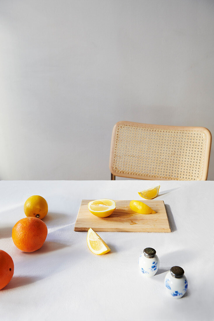 Zitronen und Orangen, ganz und aufgeschnitten auf Tisch