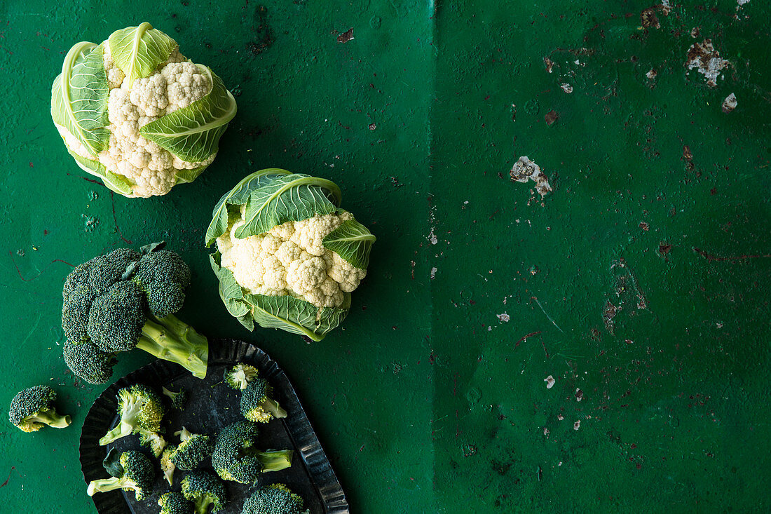 Cauliflower and broccoli on a green surface