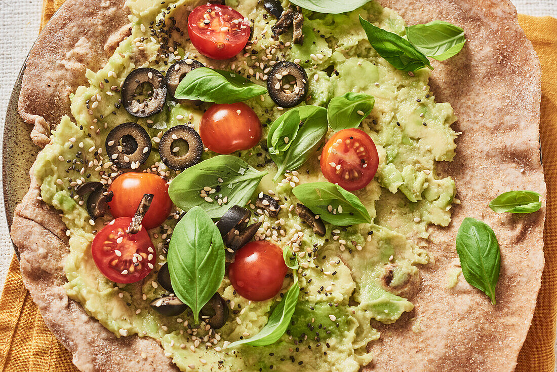 Avocado wrap with olives, cherry tomatoes and sesame seeds