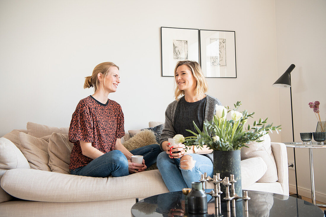 Zwei Freundinnen sitzen mit Kaffee auf der Sofa