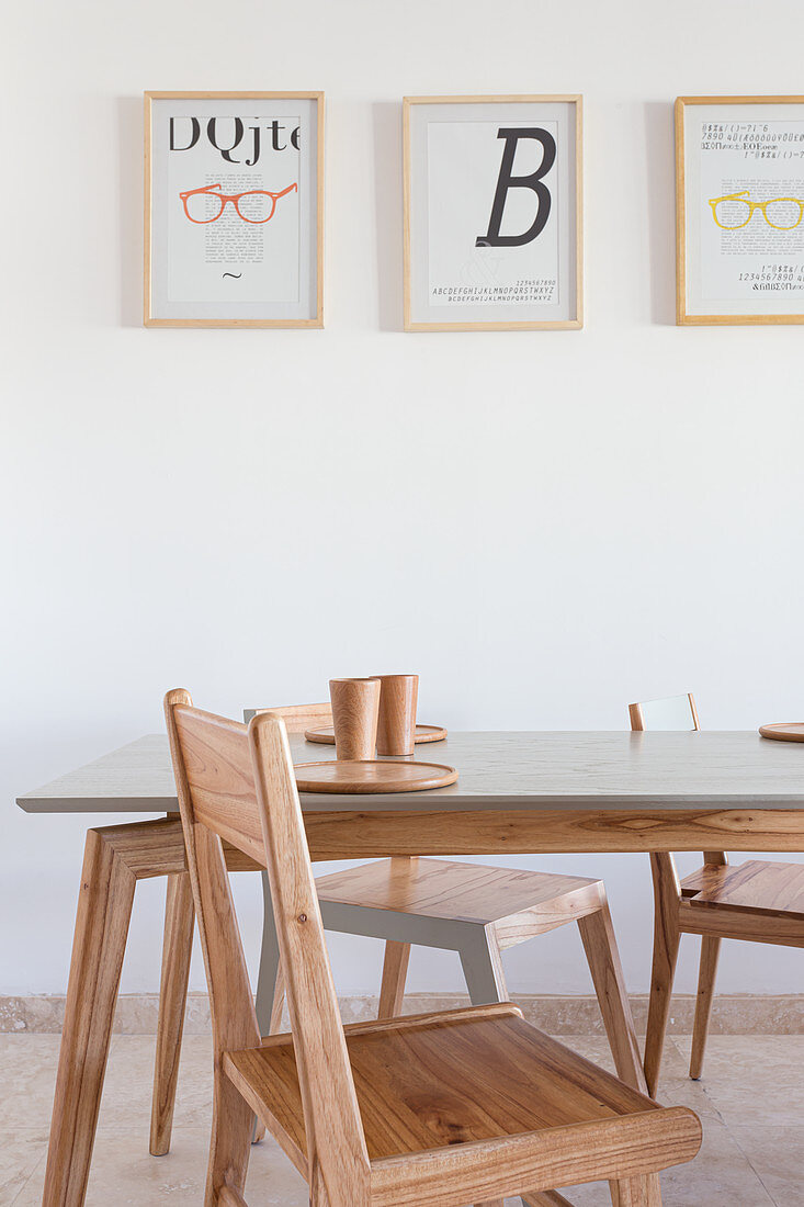 Designer chairs and dining table below modern prints on the wall