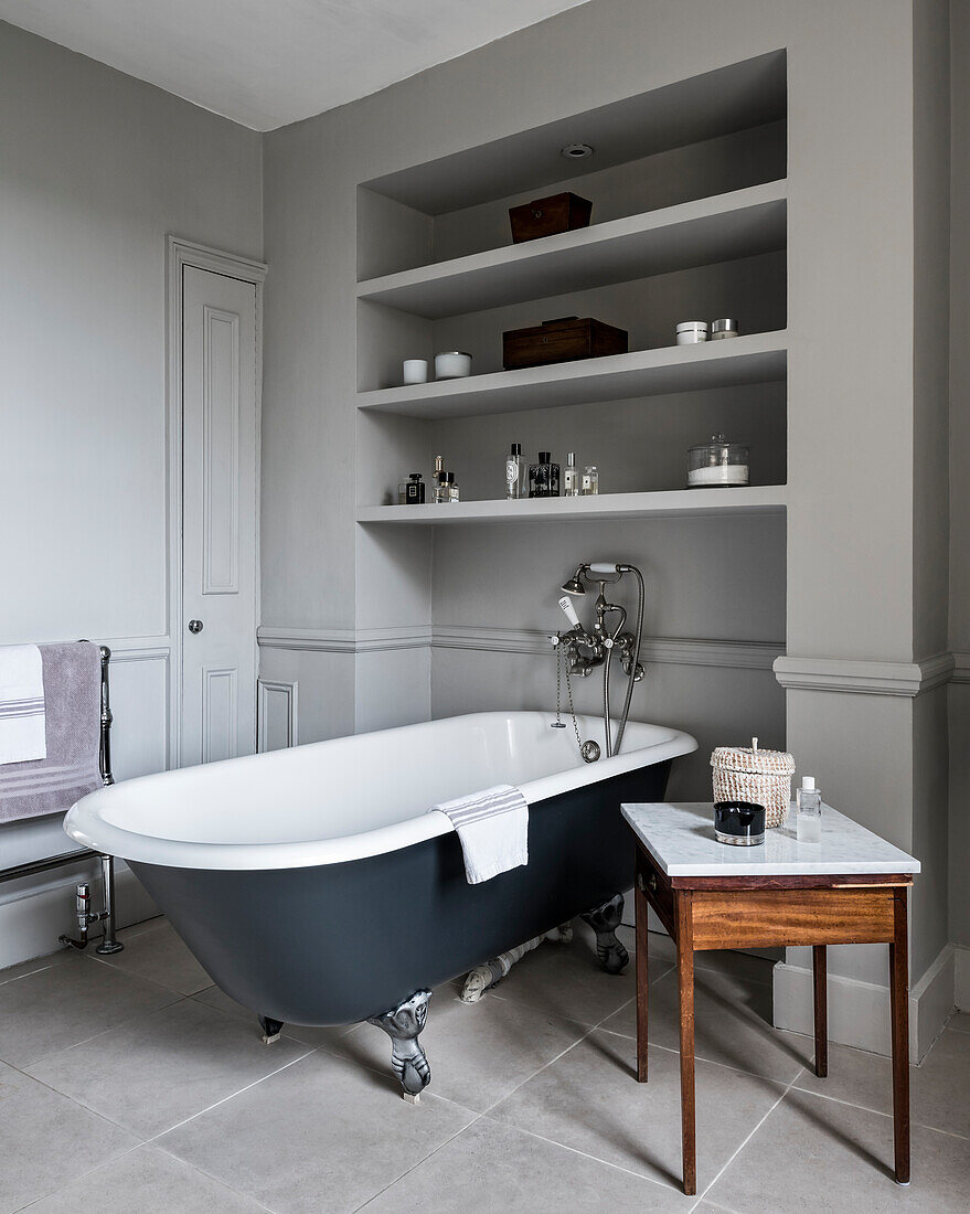 Freestanding bathtub under the shelf in the classic bathroom in grey