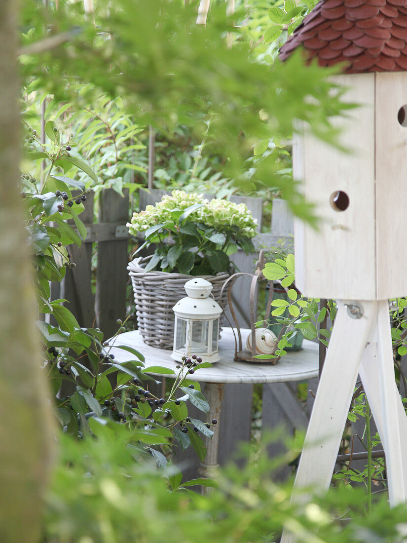 Side table with hydrangeas in basket, lantern and decorative crown