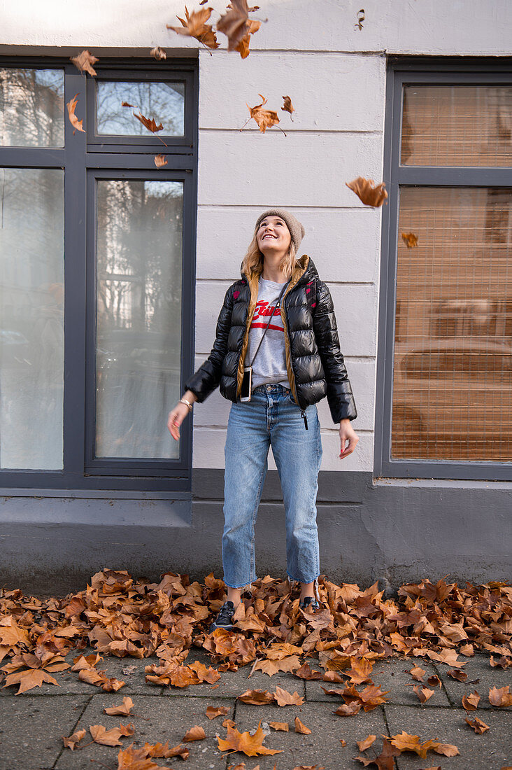 Frauen spielt mit Herbstlaub