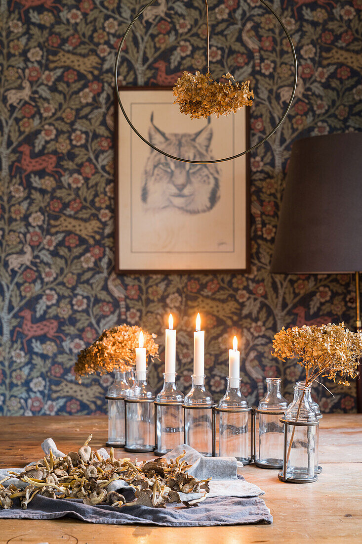Candles and dried hydrangea flowers in glass bottles on rustic wooden table