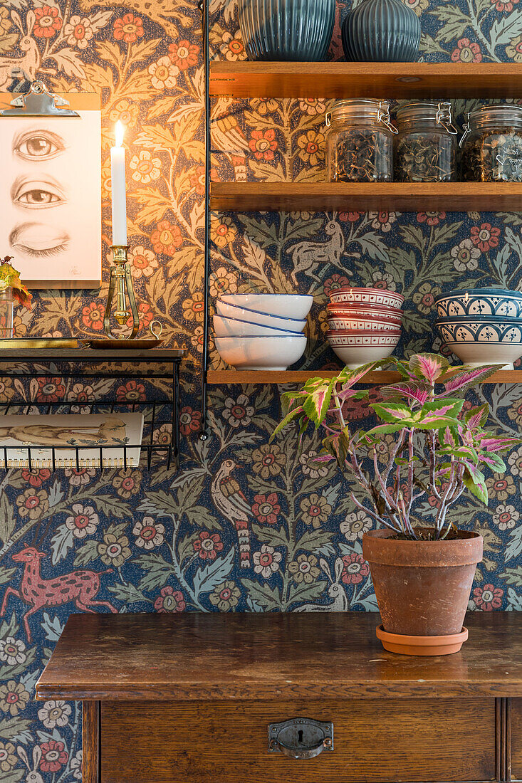 Shelf with dishes and storage jars on the wall with wallpaper