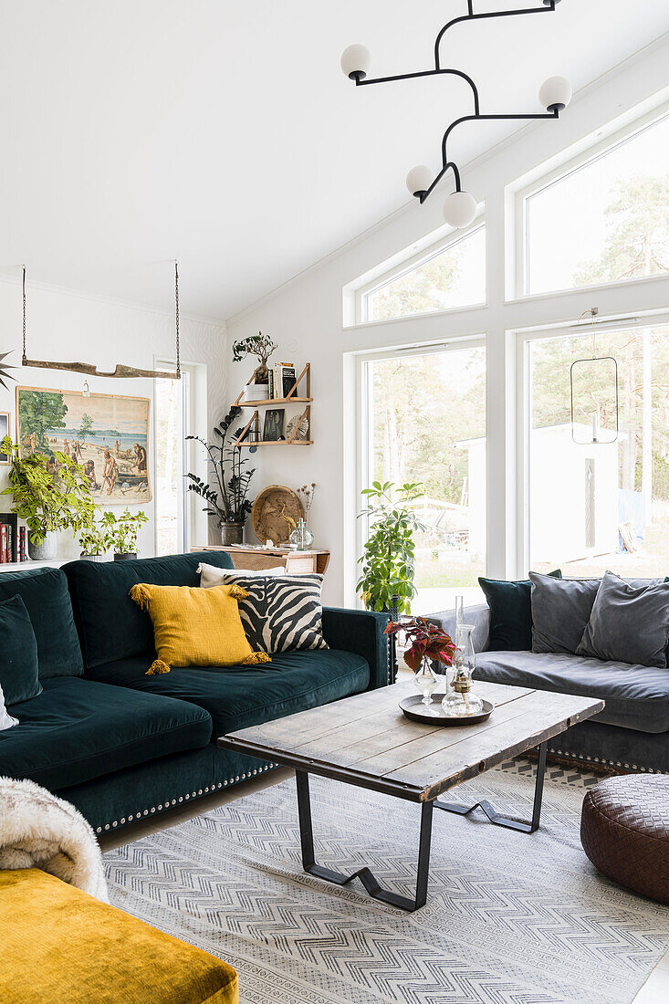 Petrolfarbenes Sofa mit Kissen und Vintage Couchtisch mit Holzplatte im Wohnzimmer