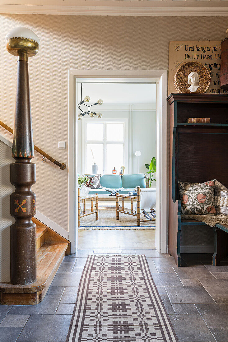 Hallway with staircase, view into living room of light blue sofa