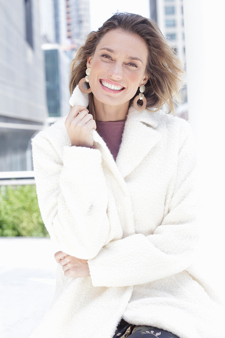 A smiling woman wearing a white coat