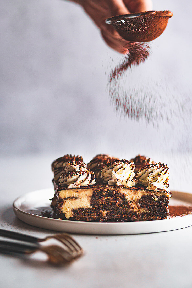 Dusting tiramisu with cocoa powder